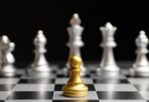 Psychiatry Criticism Politics: When the Enemy of Your Enemy Is Not Your Friend Chess photo. A gold pawn faces against a line of silver pieces