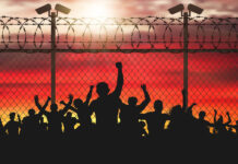 Out of Sight, Out of Mind Enraged crowd of people are behind bars. Fence wire mesh barbed wire, vector silhouette. Street camera on the pillar. Sunset background.