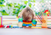 How Not to Diagnose Your Child Child with head down on table with books and school supplies, bright colors