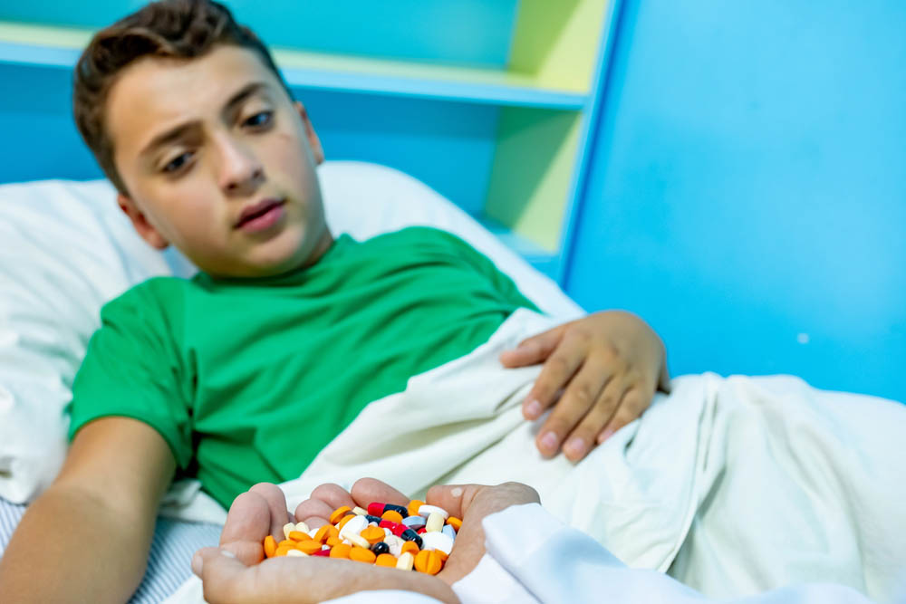 Child being given a huge handful of various pills